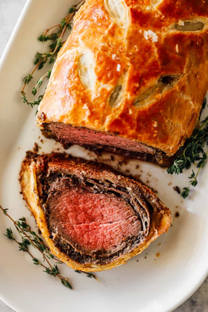 sliced beef wellington on a white serving platter.