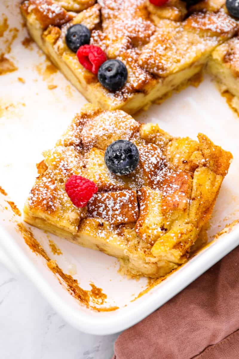 an askew slice of bread pudding in a white baking dish.