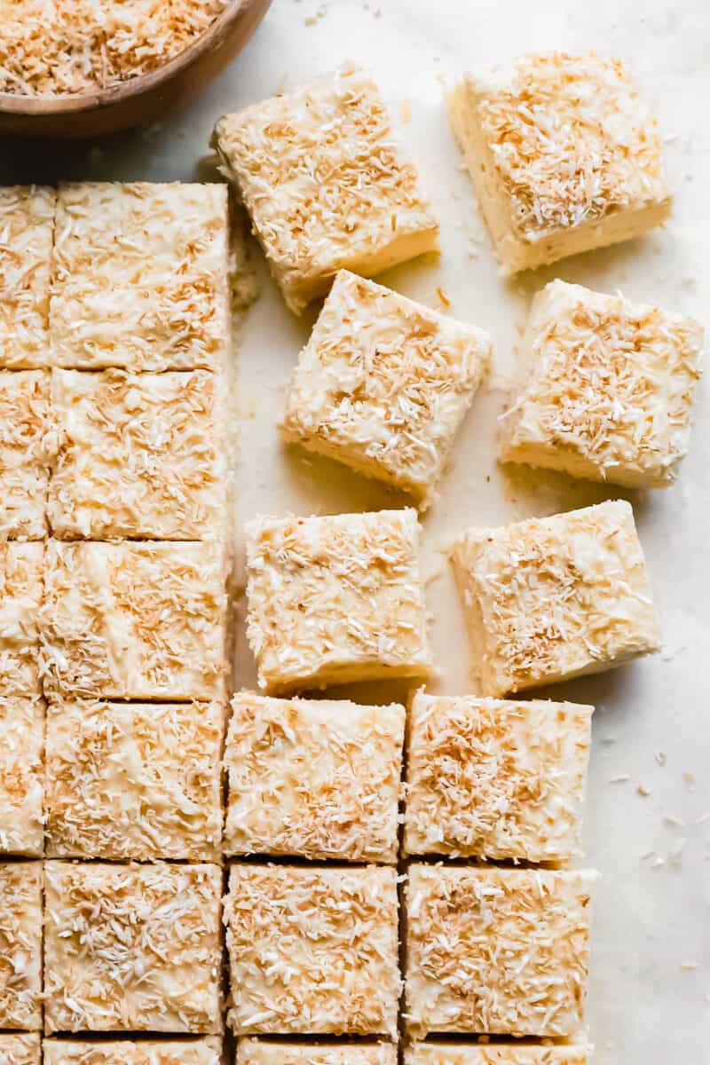 close up of cut coconut fudge on a white table.