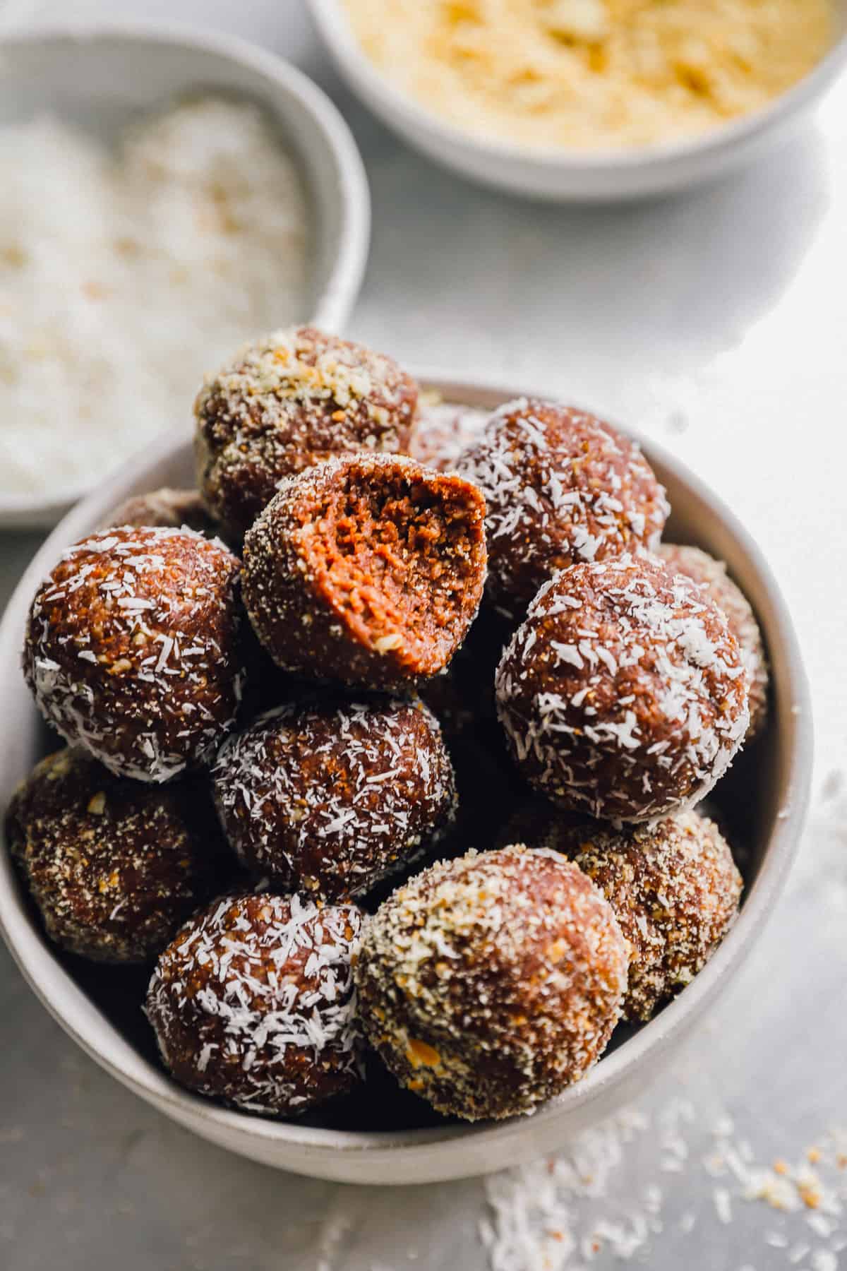 a bitten rum ball on top of a bowl of rum balls.