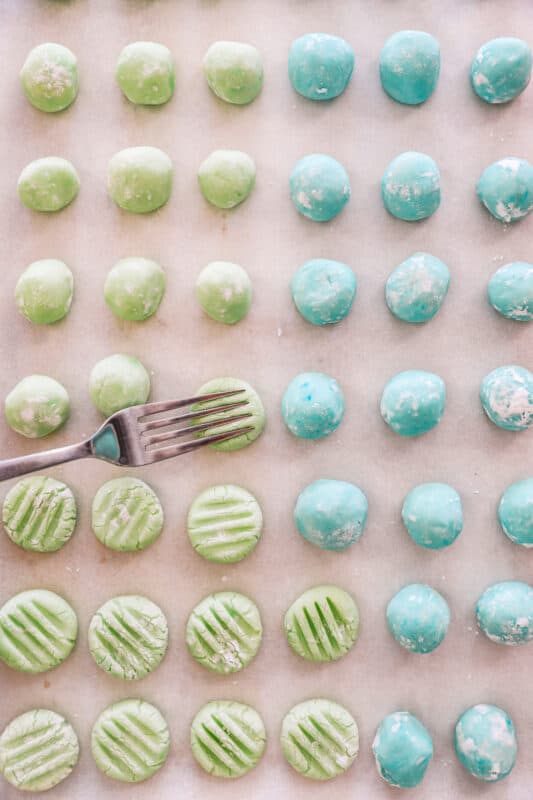cream cheese mints on a baking sheet being pressed by a fork.
