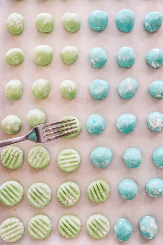 cream cheese mints on a baking sheet being pressed by a fork.