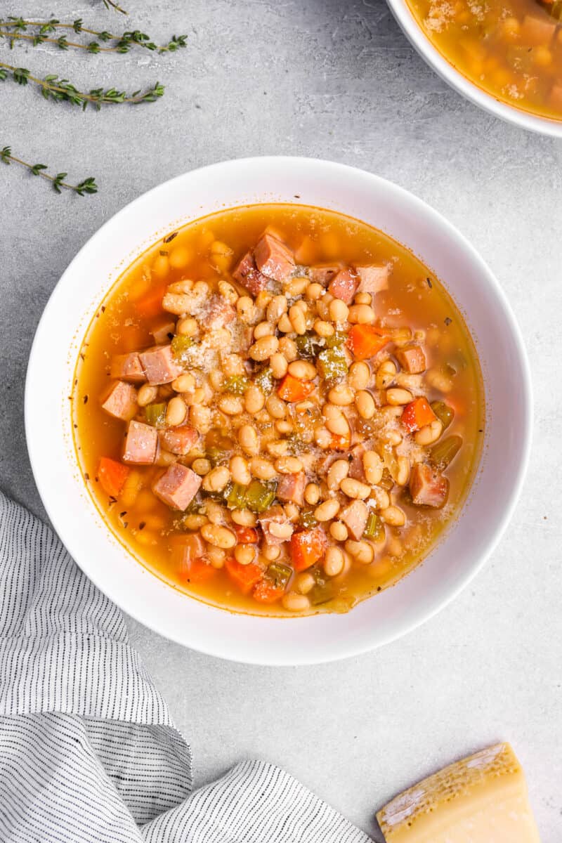 overhead view of crockpot ham and bean soup in a white bowl.