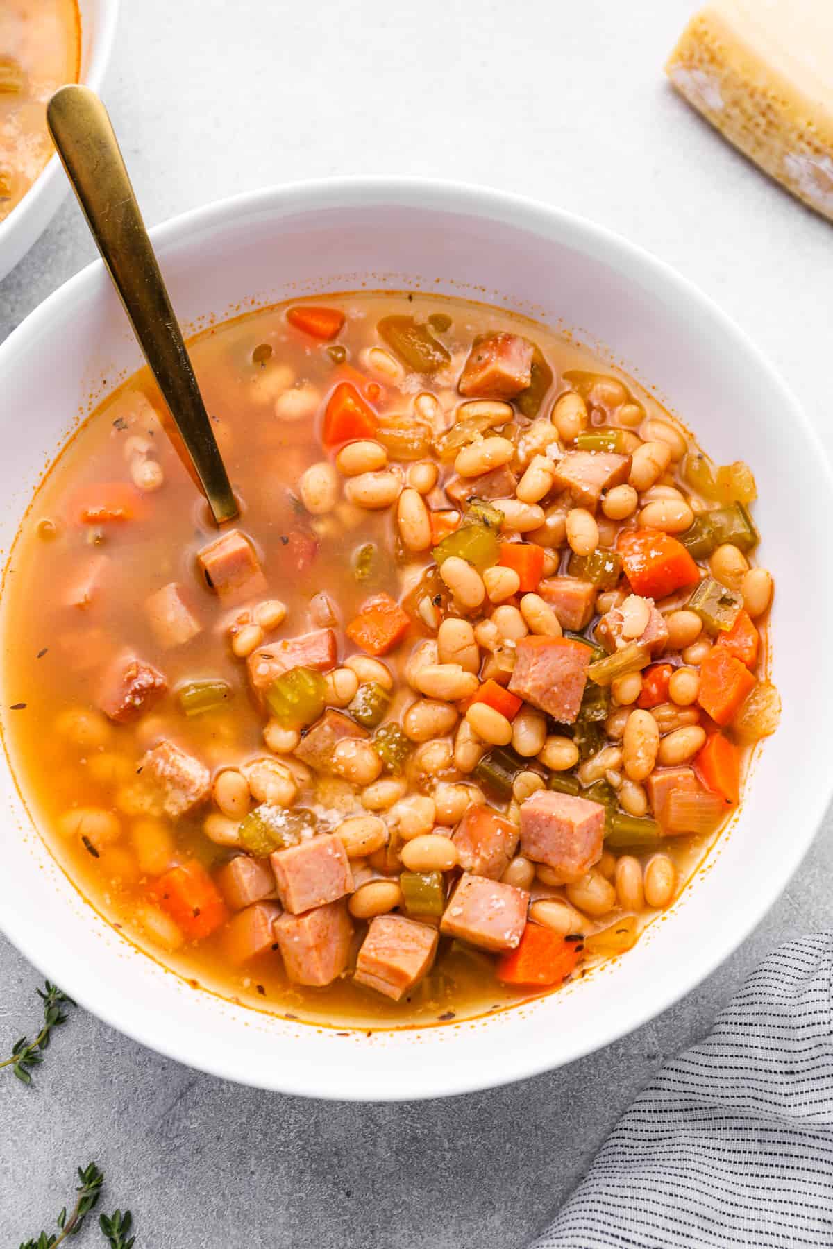 crockpot ham and bean soup in a white bowl with a spoon.
