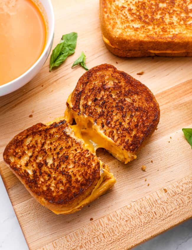 a grilled cheese cut in half on a wooden cutting board.