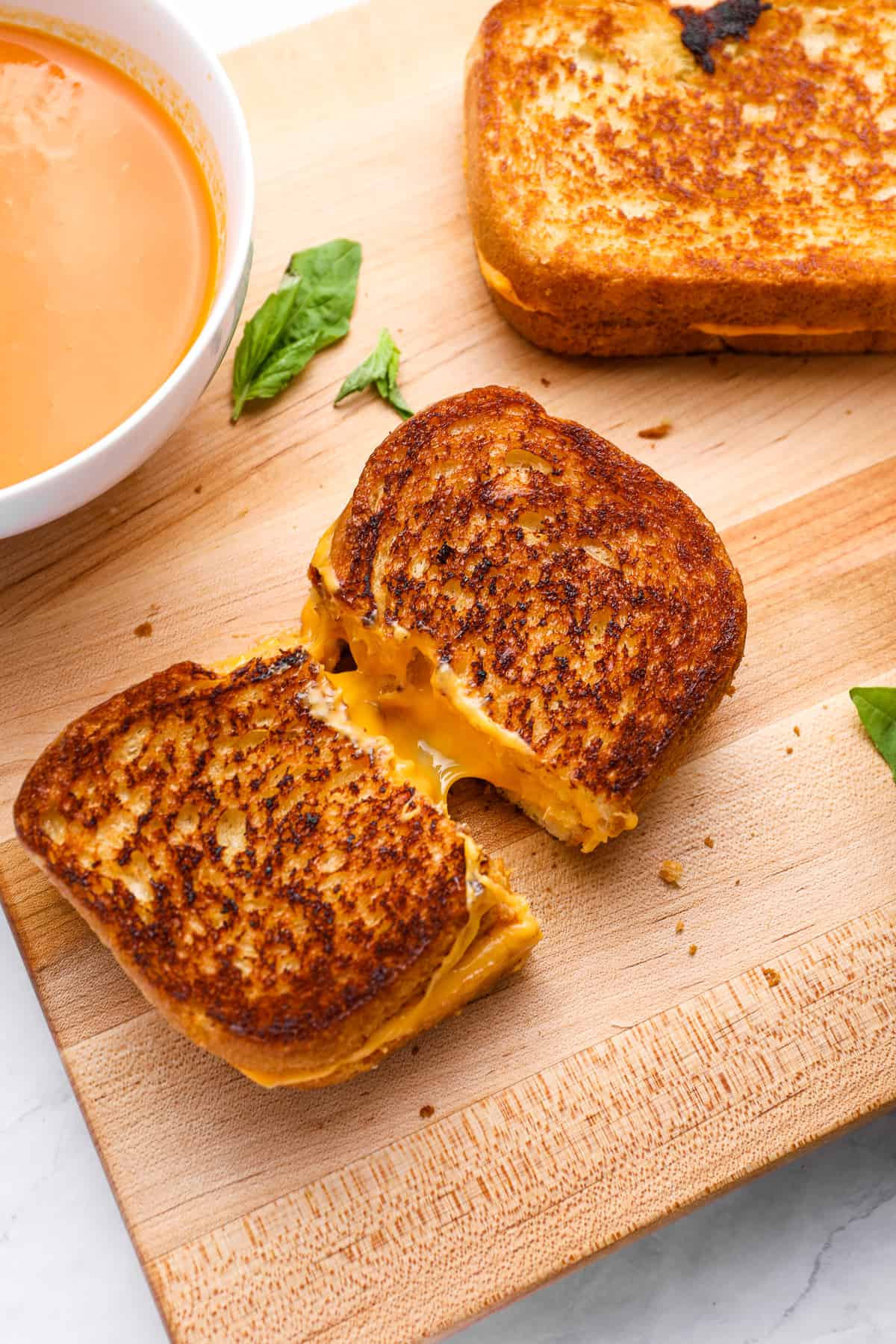 a grilled cheese cut in half on a wooden cutting board.