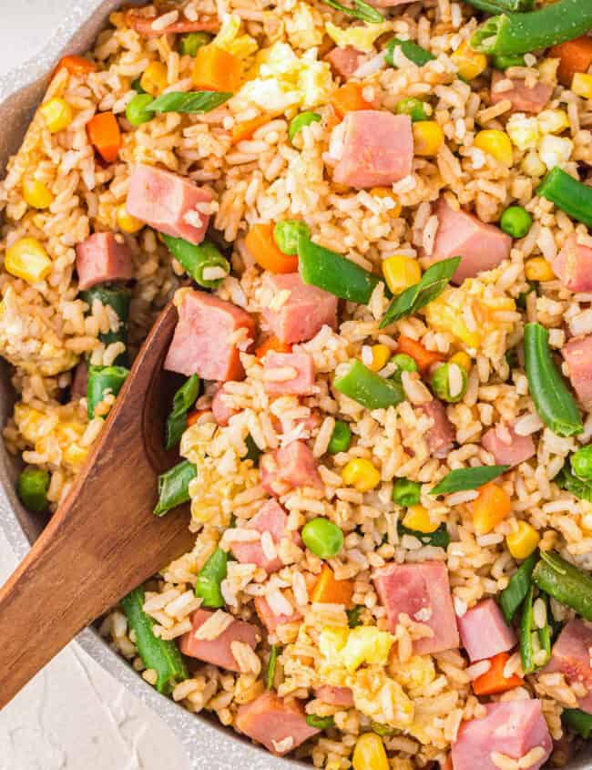 ham fried rice in a frying pan with a wooden spoon.