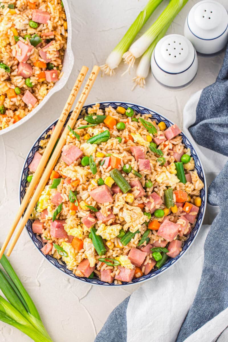 overhead view of ham fried rice in a white bowl with chopsticks.
