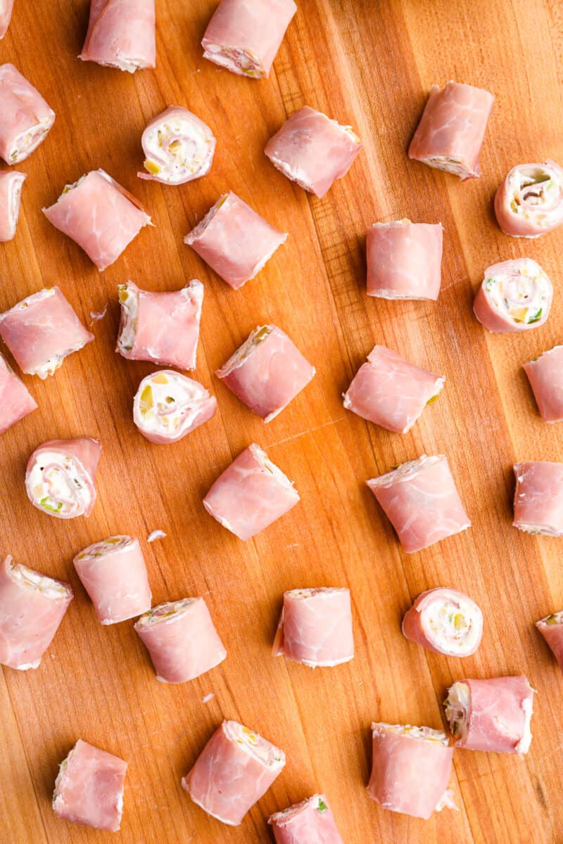 ham roll ups on a wooden cutting board.