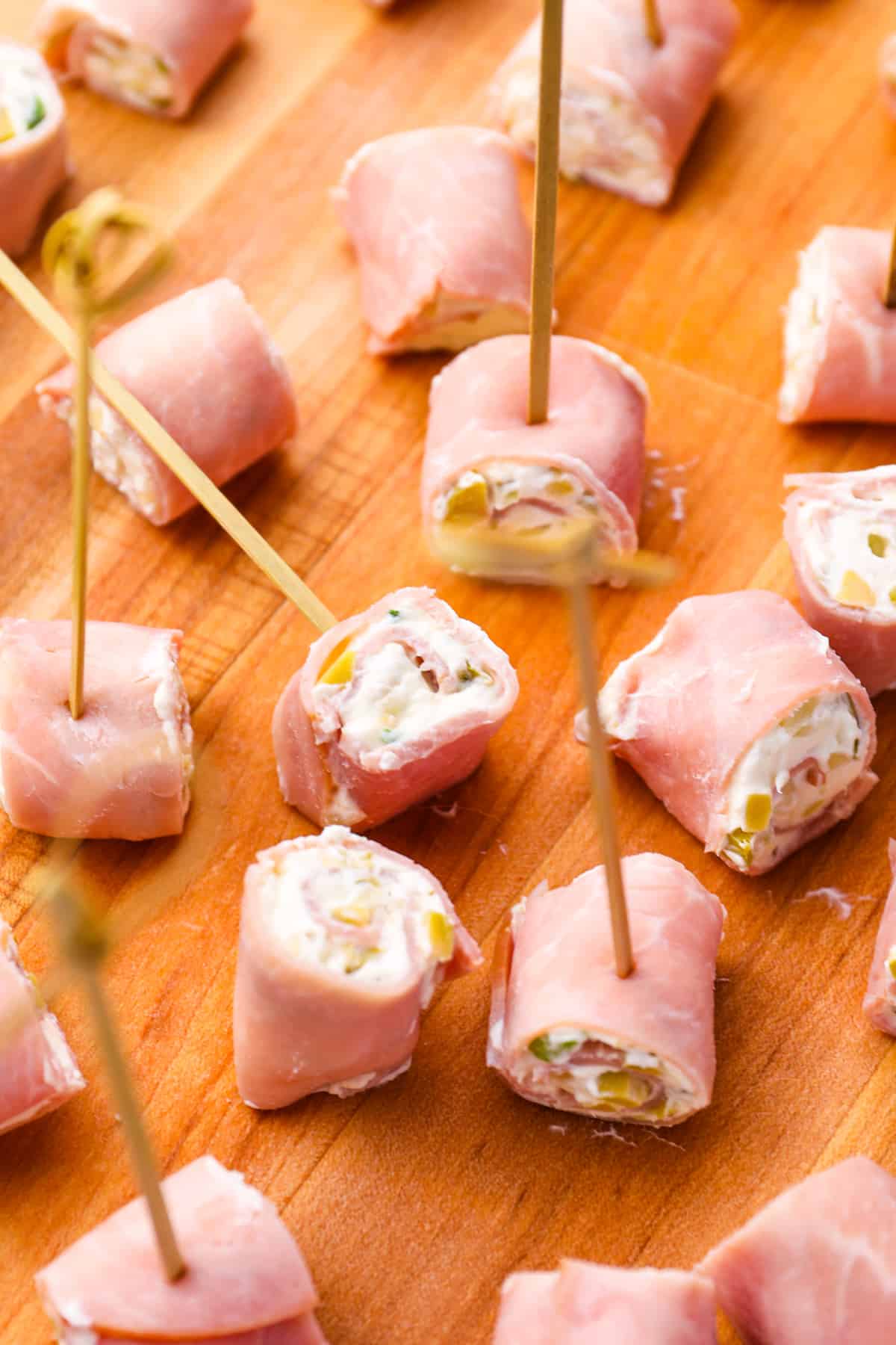 ham roll ups on a wooden cutting board.