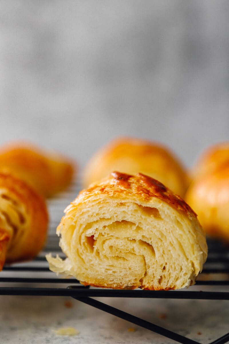 close up view of a cut croissant on a wire rack.