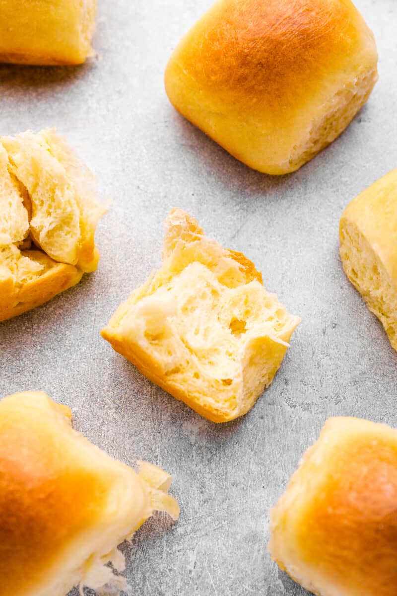 cross section of a dinner roll on a tabletop surrounded by dinner rolls.