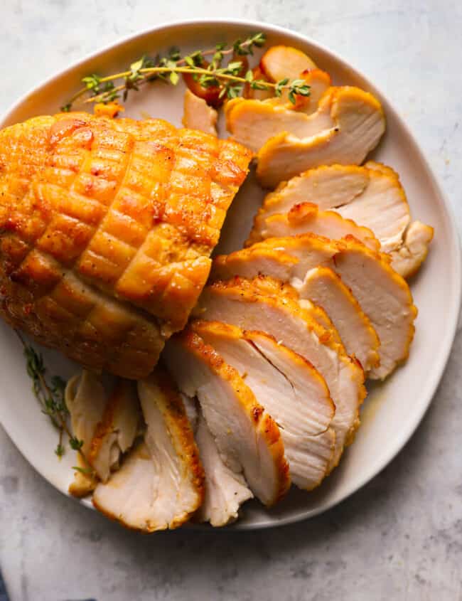 sliced honey baked turkey breast on a white serving platter.