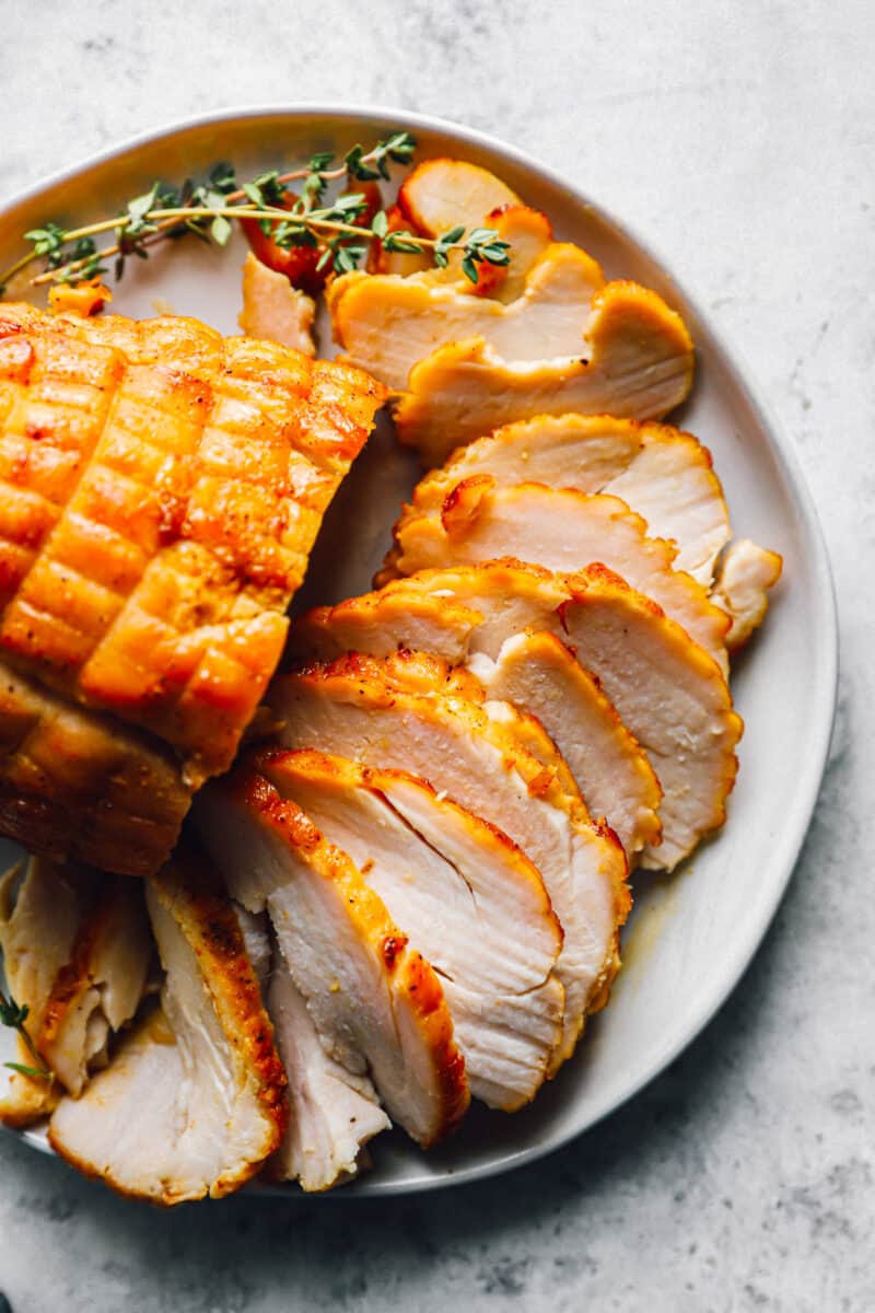 sliced honey baked turkey breast on a white serving platter.