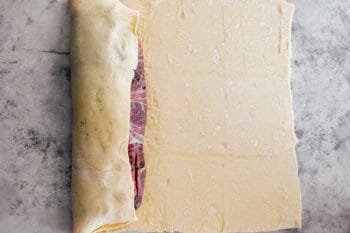 beef tenderloin being wrapped in puff pastry.