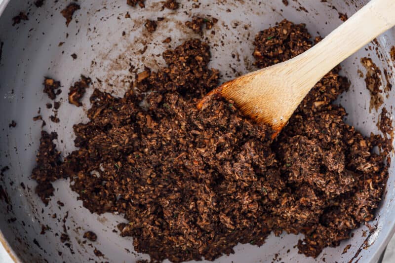 cooked mushroom mixture in a pan with a wooden spoon.