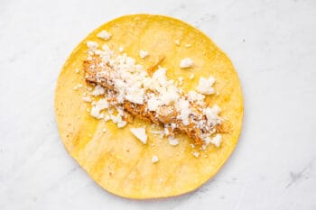 chicken and cotija cheese on top of a corn tortilla.