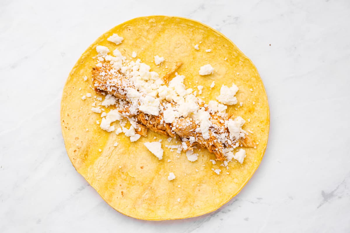 chicken and cotija cheese on top of a corn tortilla