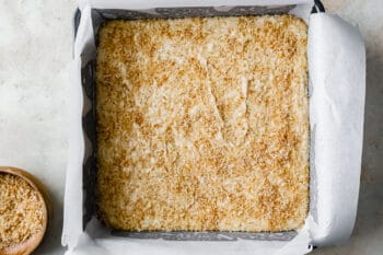 coconut fudge topped with toasted coconut in a square baking pan.