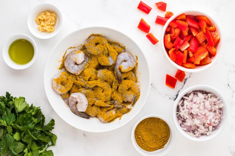 shrimp tossed with curry powder in a white bowl.