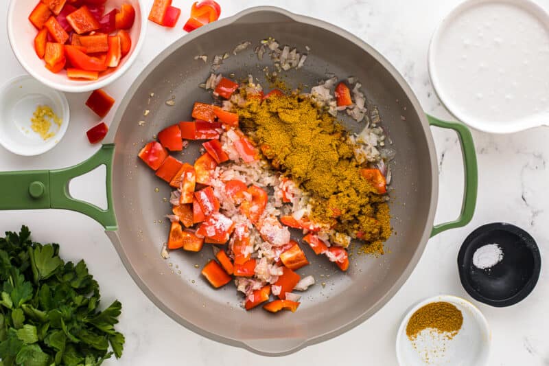 curry powder added to sauteed vegetables in a skillet.