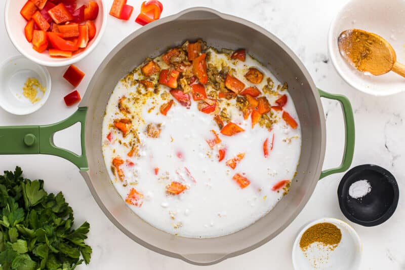 coconut milk added to sauteed vegetables in a skillet.