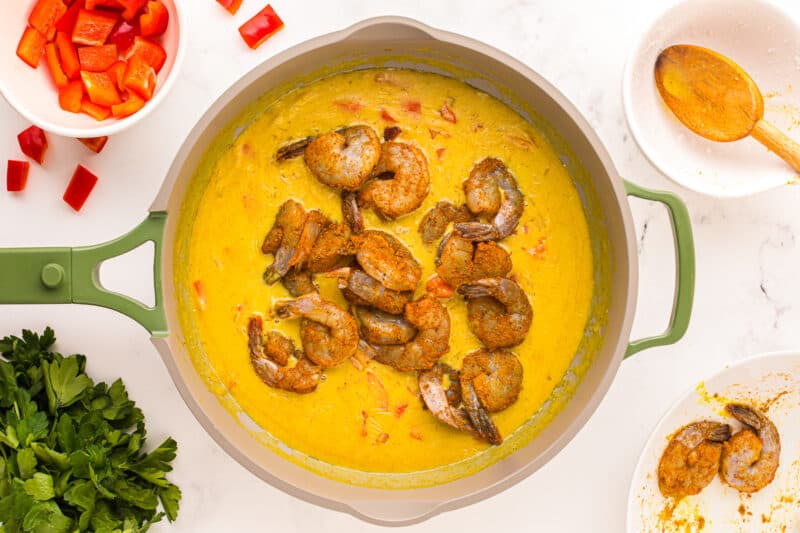 shrimp added to coconut curry sauce in a skillet.