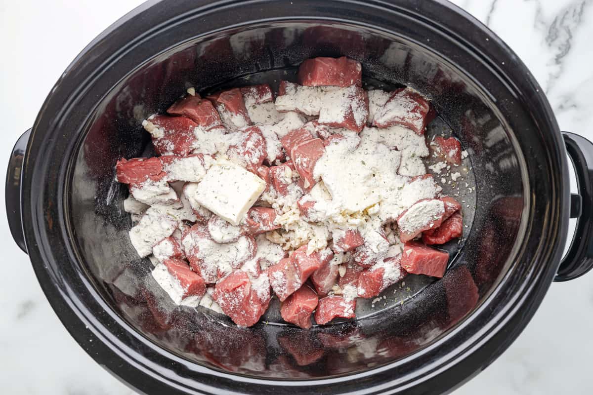 ranch seasoning on top of cubed sirloin in a crockpot.