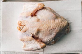 raw whole turkey on a lined baking sheet.