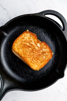 a cooked grilled cheese sandwich in a cast iron pan.