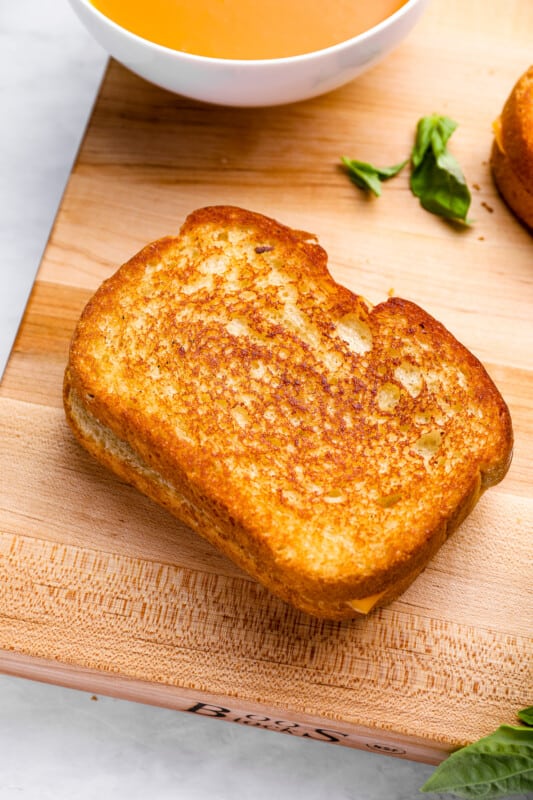 a cooked grilled cheese sandwich on a wooden cutting board.