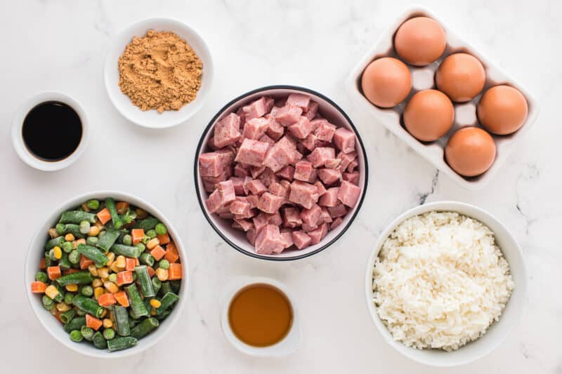 overhead view of ingredients for ham fried rice in individual bowls.