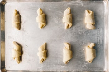 8 unbaked croissants on a baking sheet.