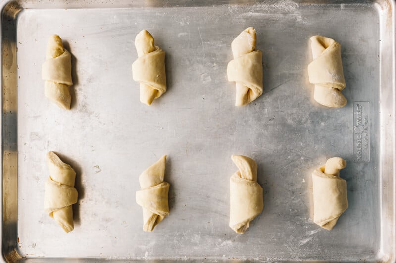 8 unbaked croissants on a baking sheet.