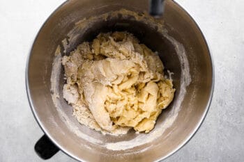 roughly mixed dinner roll dough in a stainless mixing bowl.