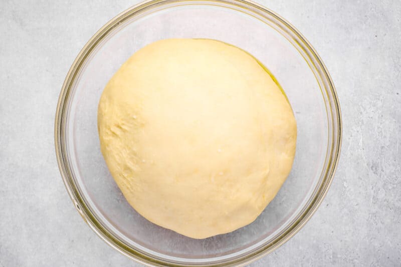proofed dinner roll dough in a glass bowl.