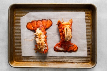 two cooked lobster tails on a baking sheet.