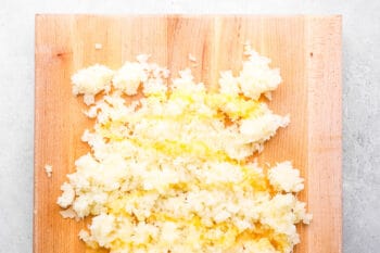 shredded potatoes with egg on a wooden cutting board.