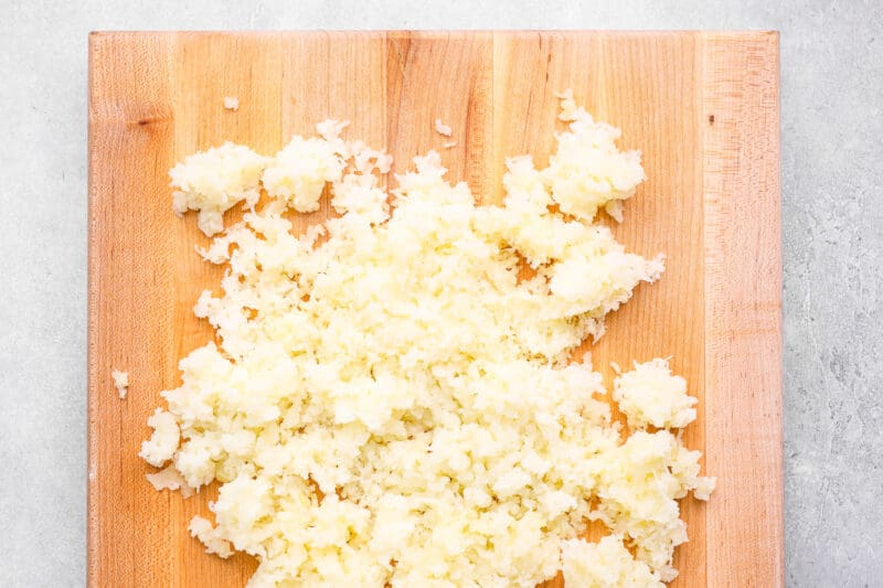 shredded potatoes on a wooden cutting board.