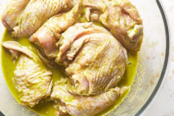 close up on chicken thighs marinating in a large bowl