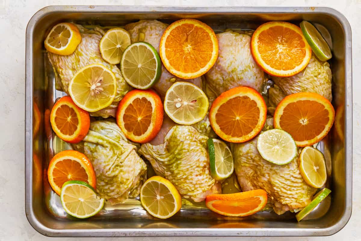 overhead view of marinated chicken and citrus slices arranged in a deep baking dish, before cooking