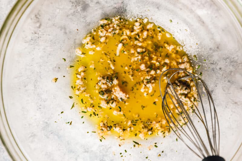 oil and seasonings for roasted mushrooms in a glass bowl with a whisk.