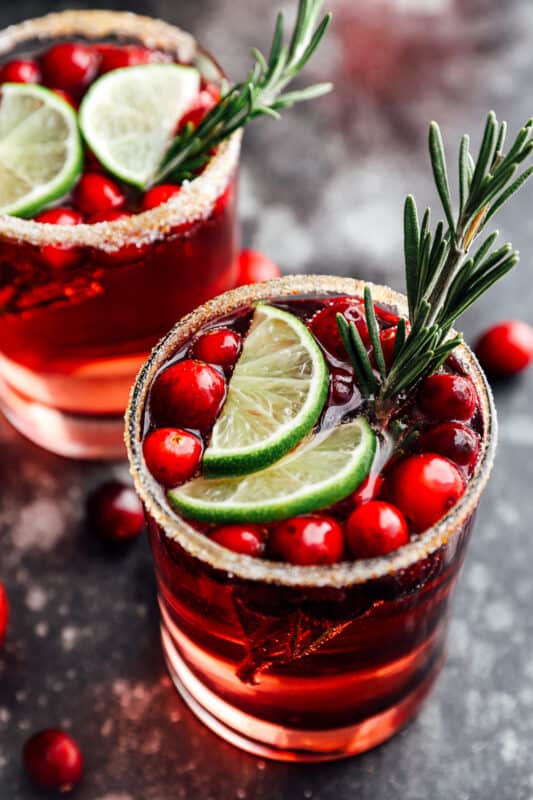 2 glasses of jingle juice garnished with lime slices and rosemary sprigs.