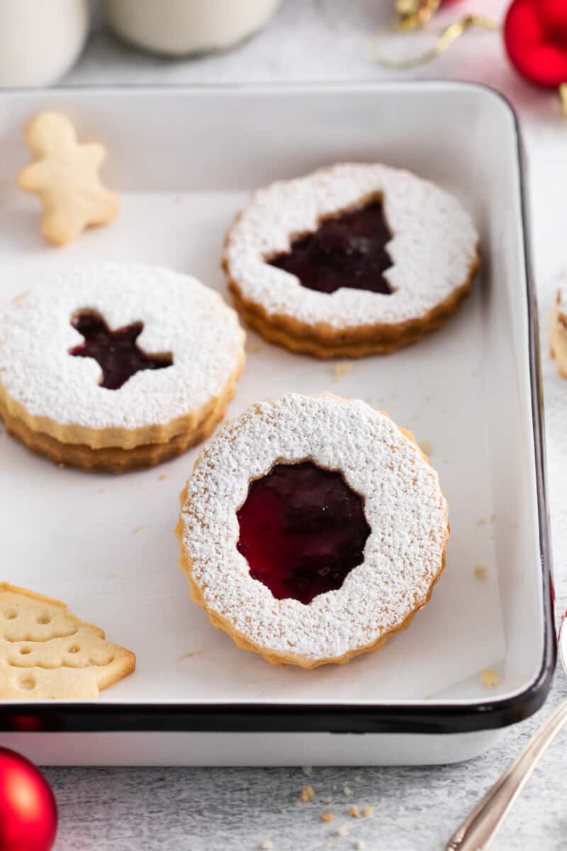 linzer cookies with shapes cut out of the middle, on a baking tray