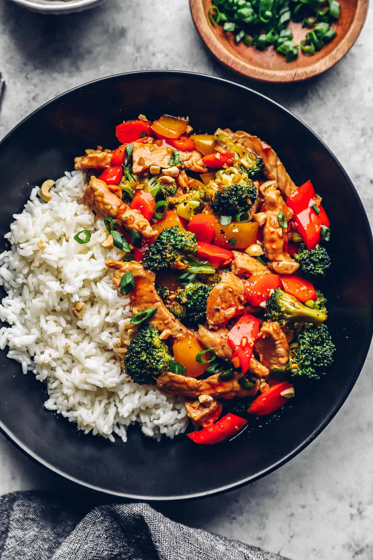 pork, broccoli, and bell peppers with white rice in a black bowl.