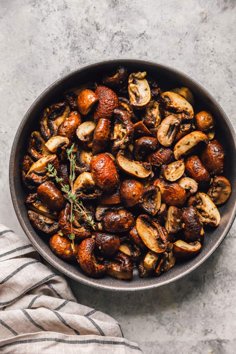 overhead view of roasted mushrooms in a gray serving bowl.