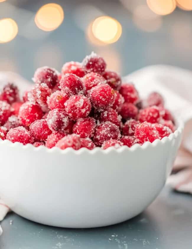 Sugared cranberries in a white bowl on a table.