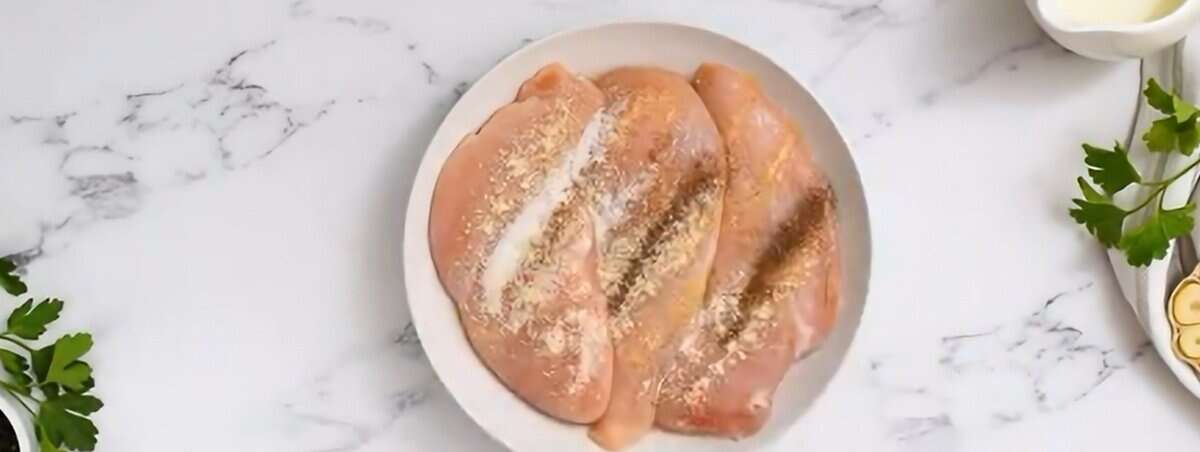 Seasoned chicken breasts on a white plate.  - 6