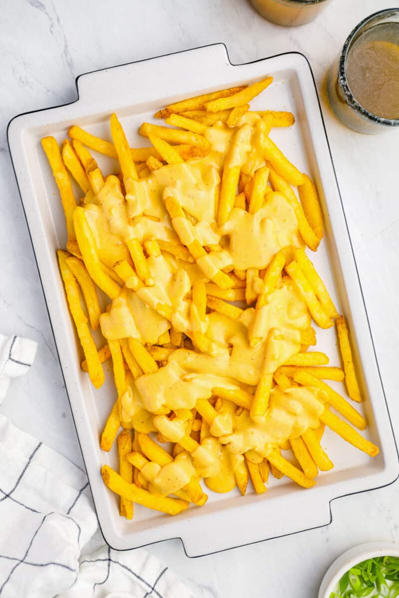 overhead view of cheese fries on a white rectangular serving dish.