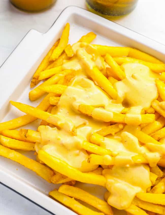 partial view of cheese fries on a white rectangular serving dish.